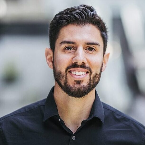 Headshot of a man in a black shirt and a beard