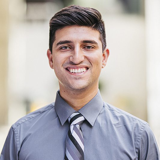 Headshot for Vicente. He is wearing a grey shirt with a grey and black striped tie.